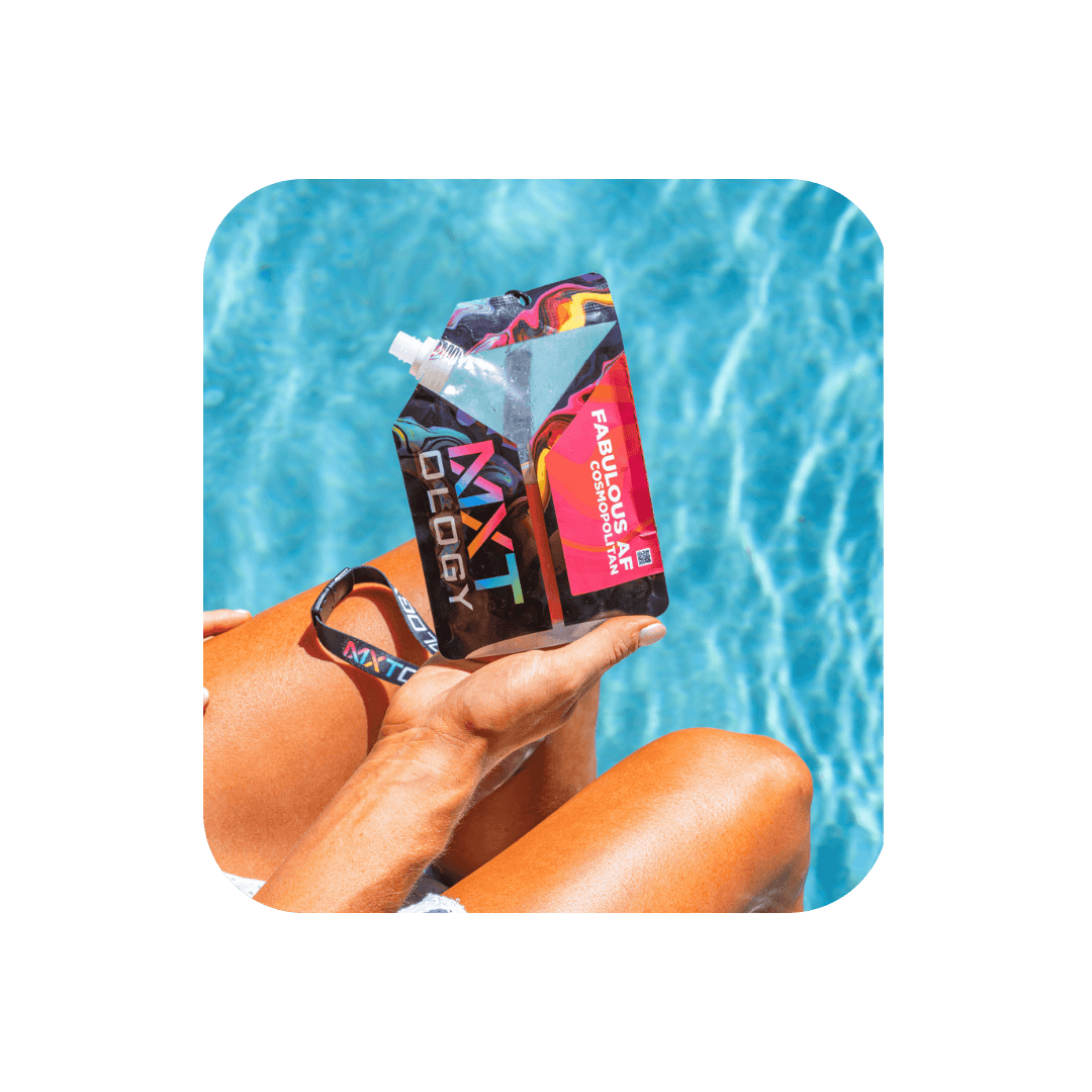 Person relaxing poolside holding MXTology Fabulous AF Cosmopolitan cocktail pouch, enjoying summer vibes by the water.