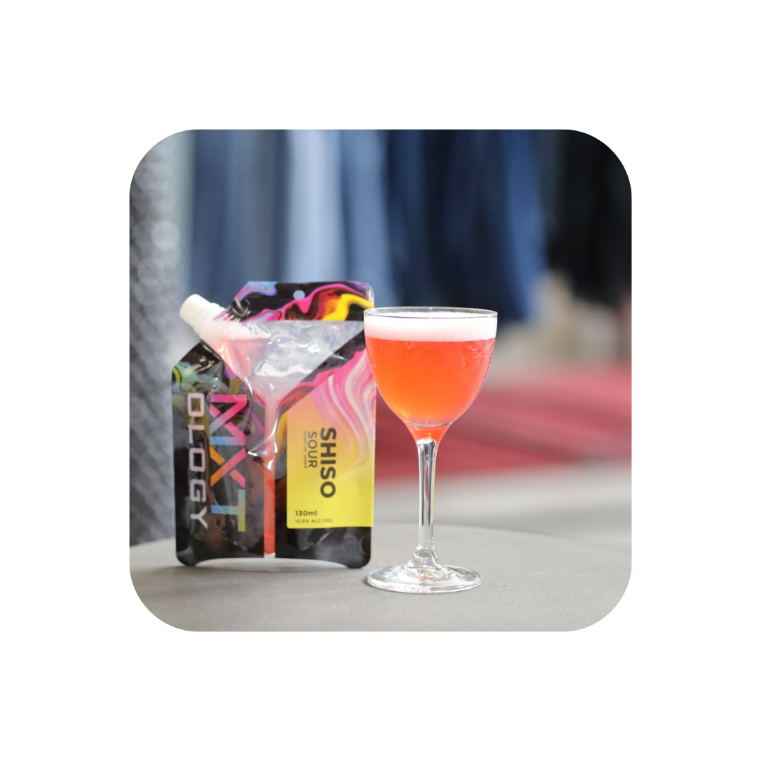 MXTology Shiso Sour cocktail pouch and freshly poured cocktail glass on table, vibrant background.